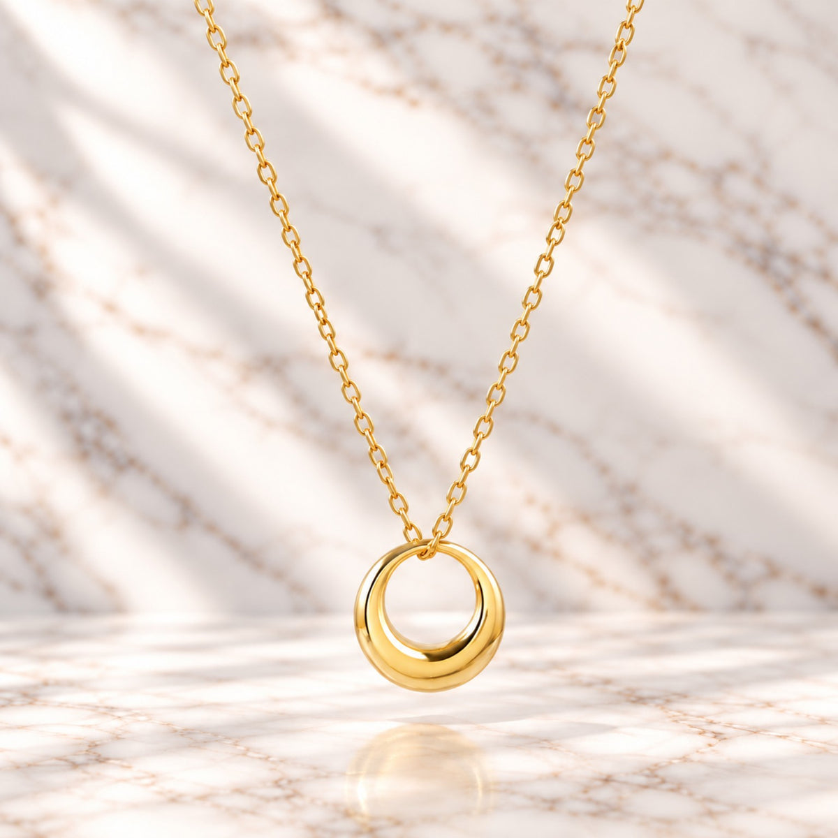 Collier fin doré à pendentif anneau bombé sur marbre blanc