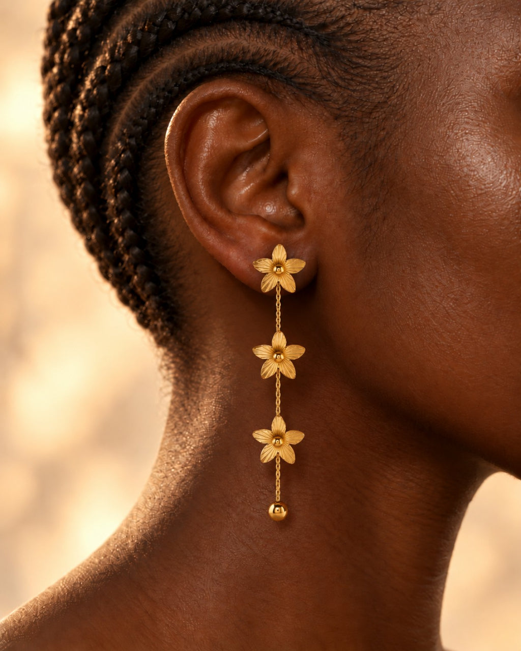 Boucles Floraison à trois fleurs dorées portées en gros plan