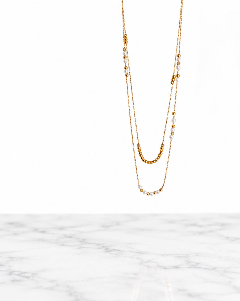 Collier Accord double rang doré et perles blanches sur fond blanc