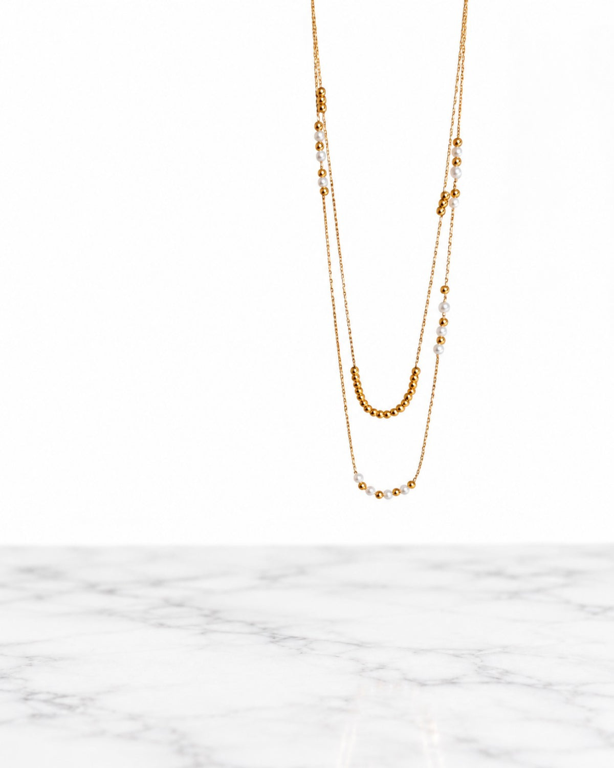 Collier Accord double rang doré et perles blanches sur fond blanc